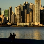 A city with red rooftops in the foreground and skyscrapers in the background